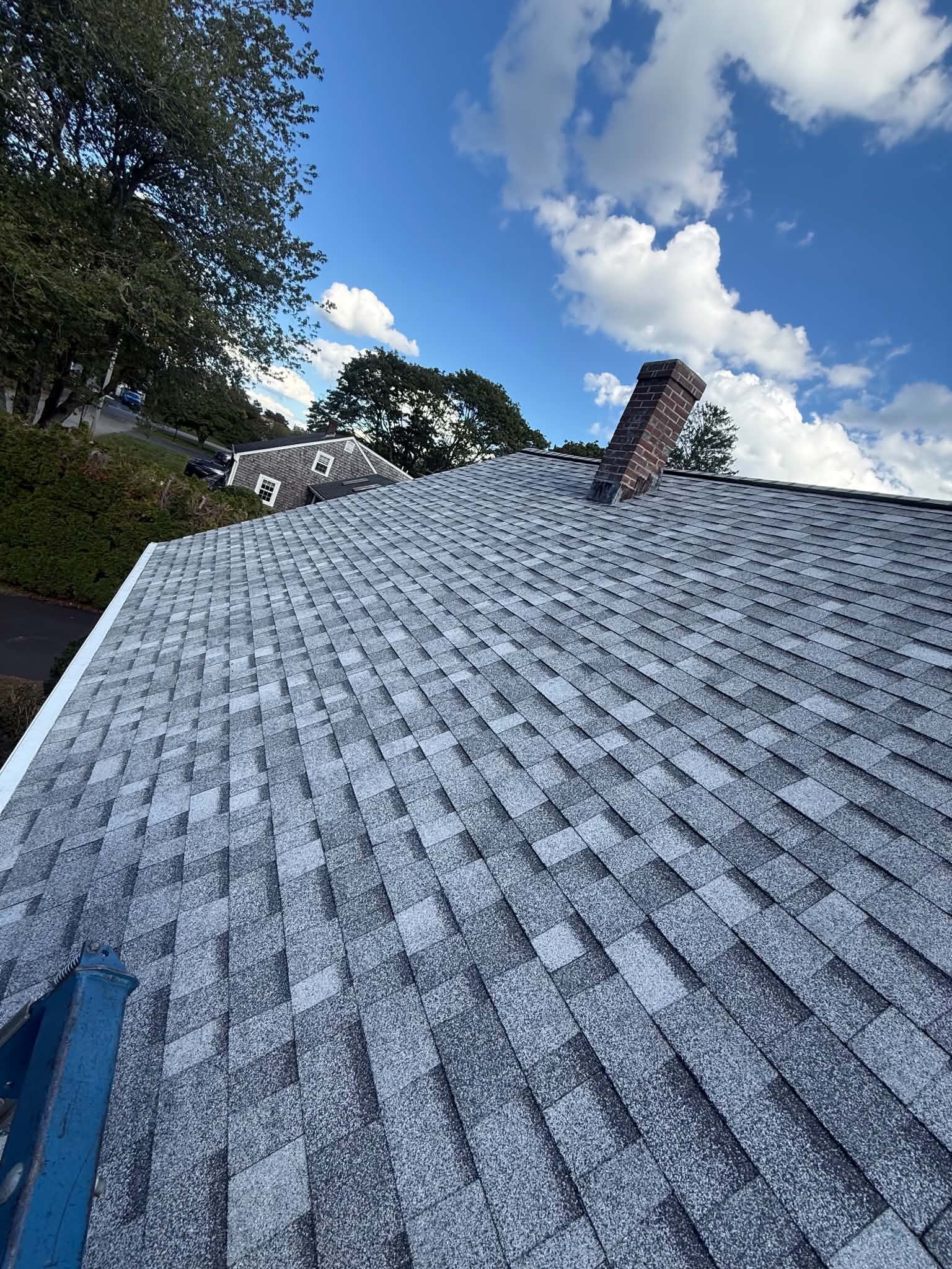 Projects New gray shingle roof and chimney under blue sky in Massachusetts