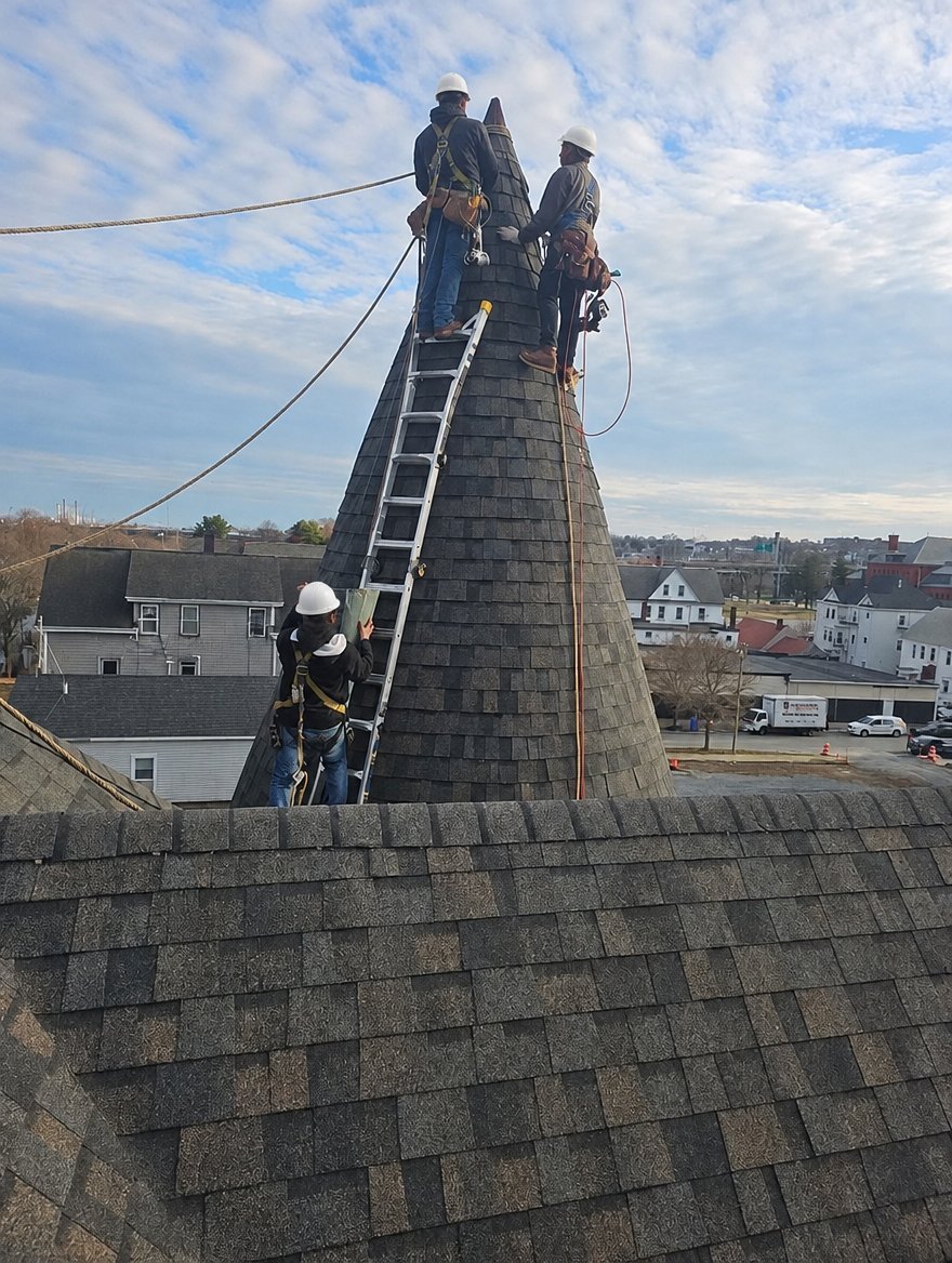 Daniela's Construction roofing crew with hard hats and harnesses finishing a turret roof in Massachusetts